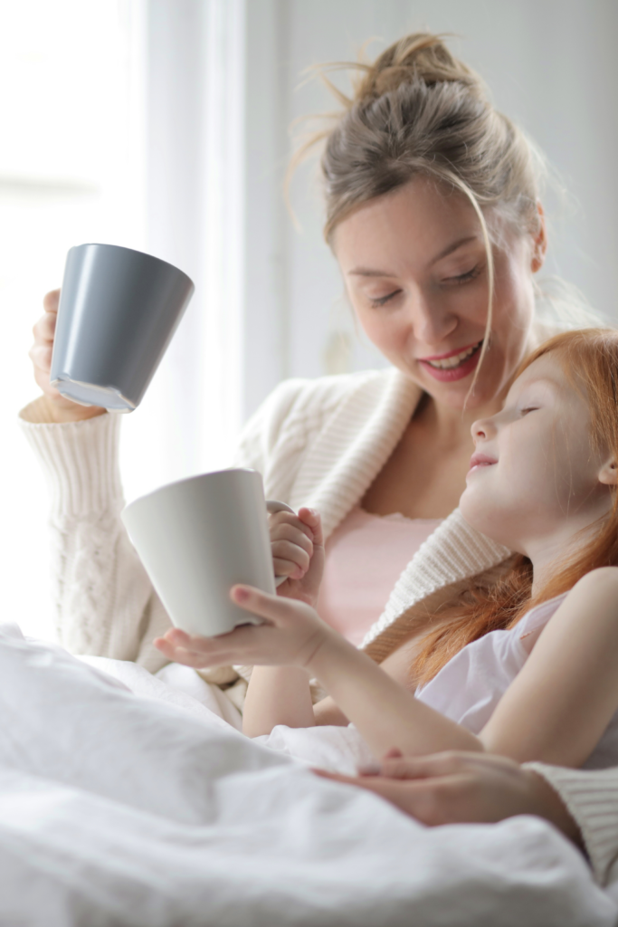 Mom and kid talking on the bed, holding a mug while talking